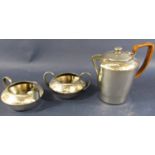 A Tudric hammered pewter three piece tea service consisting of a teapot, milk jug and sugar bowl.