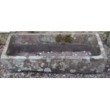 An unusual weathered natural stone trough of rectangular wedge shaped form with central