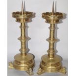 A pair of Victorian ecclesiastical Gothic candle sticks, with crenellated sconces raised on three