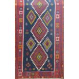 A Qashgai Kilim carpet with a repeating multi coloured diamond pattern. 310cm x 135cm