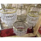 Two Edwardian style three tier crystal bag chandeliers, one smaller than the other and a single