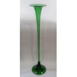 A tall slender green glass trumpet vase on a pad foot, 120cm high