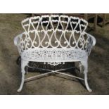 Small decorative cream painted cast iron garden bench with pierced scrolling foliate detail and