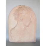 A terracotta arched panel moulded in relief of the profile of a curly haired youth. 43cm high x 32cm