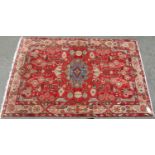 A Persian designed carpet with an all over stylised floral pattern and a central blue medallion on a