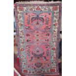 An old Middle Eastern rug with a stylised floral motif on a pink ground,180cm x 100cm approx