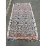 An old Kilim, with a diamond panelled repeating pattern, 260cm x 134cm approx (AF tears and holes)