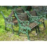 A set of four garden chairs with stained hardwood lathes and raised on decorative green painted cast