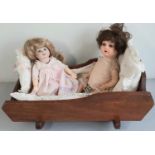 2 small bisque head dolls with a vintage wooden rocking crib; one doll has head marked 'SFBJ 252