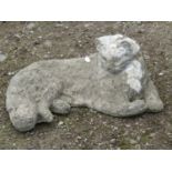 A weathered composition stone life size garden ornament in the form of a recumbent cat, 47 cm long x