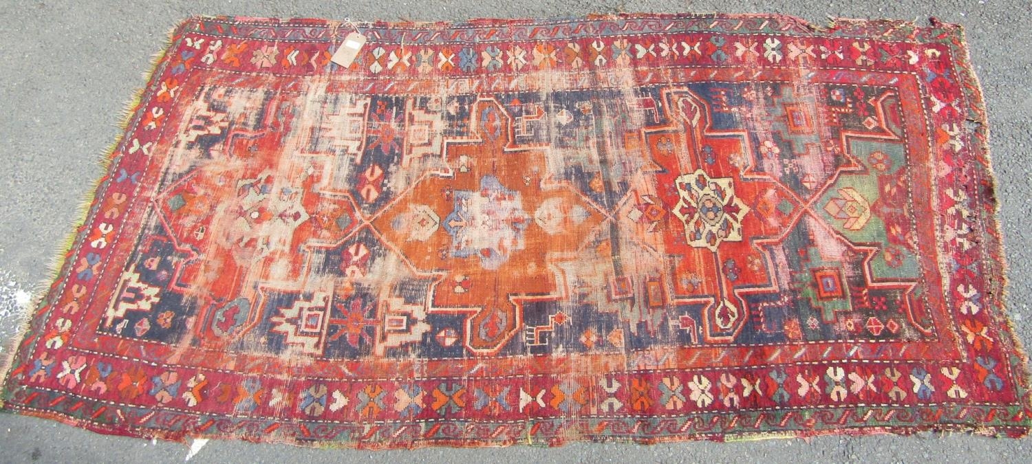 An old Persian rug with a central orange medallion,245cm x 120cm approx