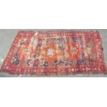 An old Persian rug with a central orange medallion,245cm x 120cm approx