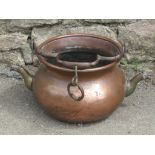 A 19th century copper cauldron with loose looped brass handle with female mask detail and twin spout