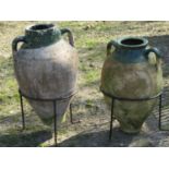 A weathered terracotta Turkish amphora with moulded loop handles, green glazed neck and set in a