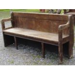 A stained pine chapel bench with open shaped and moulded arms, panelled back, chamfered legs, 190 cm