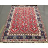 A large Kazak carpet with three rows of geometric crosses on a red ground, 360cm x 260cm approx