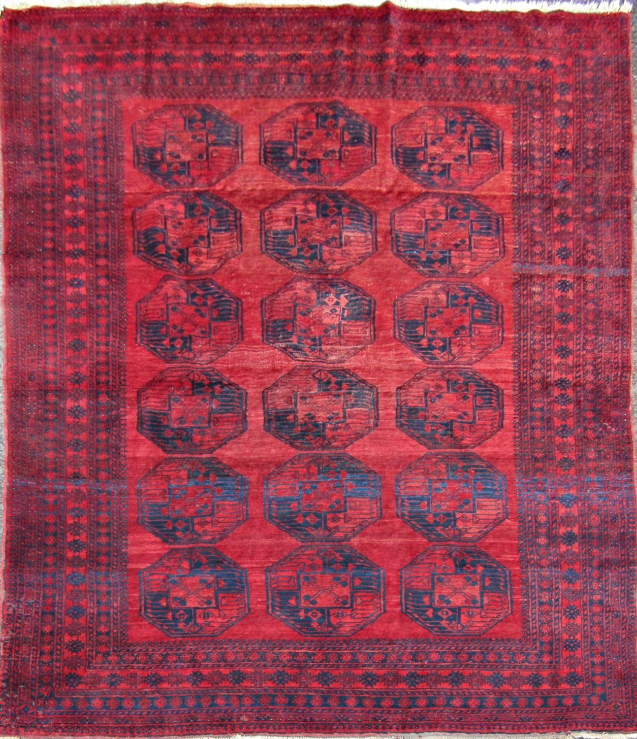A large Afghan designed carpet with a central panel of elephant feet on a red ground. 310cm x