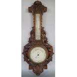 A Victorian aneroid barometer by Dolland London with carved walnut frame