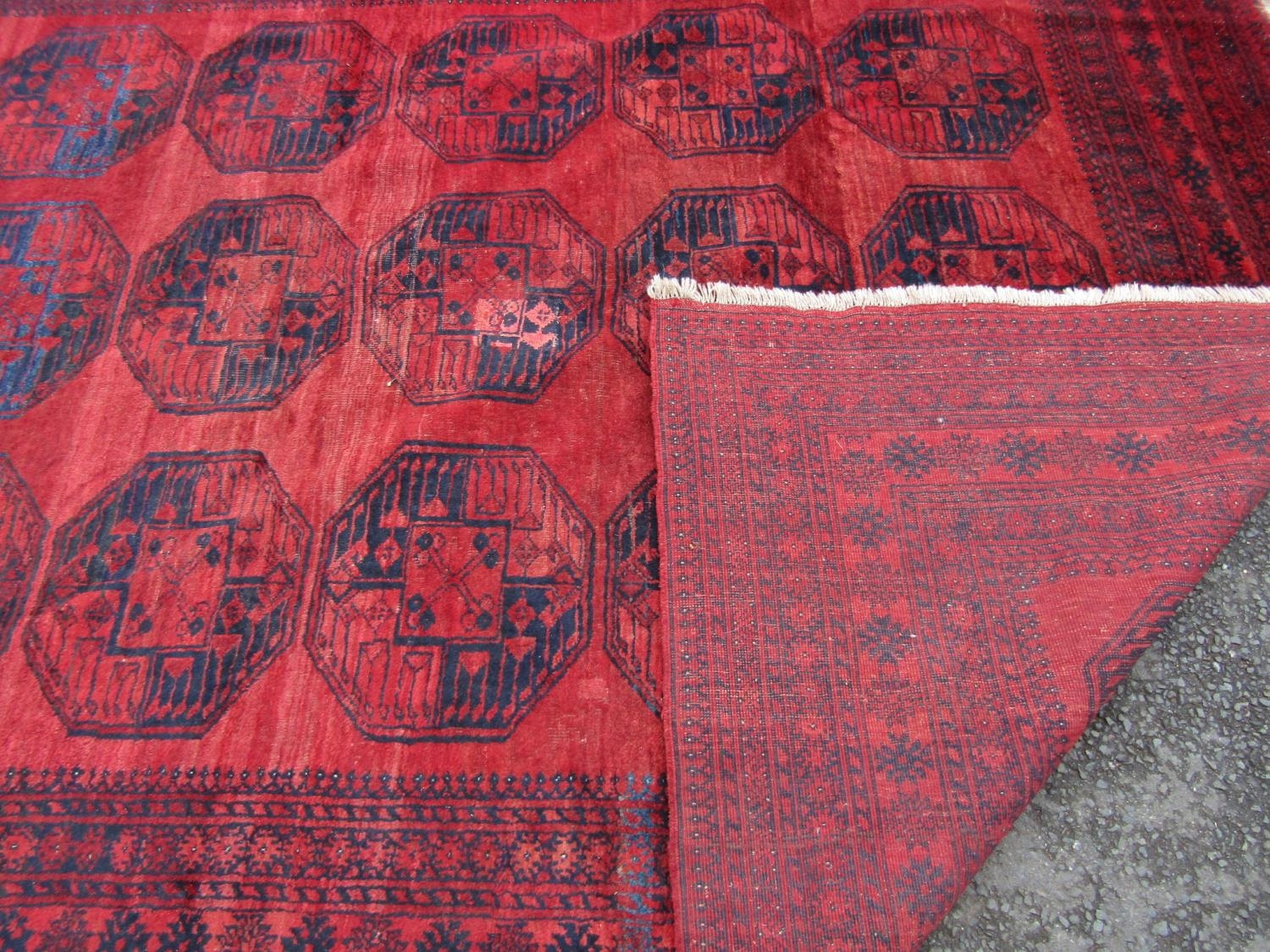 A large Afghan designed carpet with a central panel of elephant feet on a red ground. 310cm x - Image 3 of 3