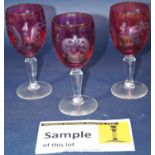 Eleven cranberry with scrolled etched decoration wine glasses on clear stems, a cut glass claret