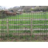 A pair of large ironwork entrance gates with vertical square cut and partially rope twisted bars