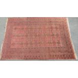 An old Turkoman rug with alternating small medallions on a faded pink ground, 200cm x 132cm approx