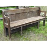 A stained pine chapel bench with open shaped and moulded arms, panelled back, chamfered legs, 190 cm