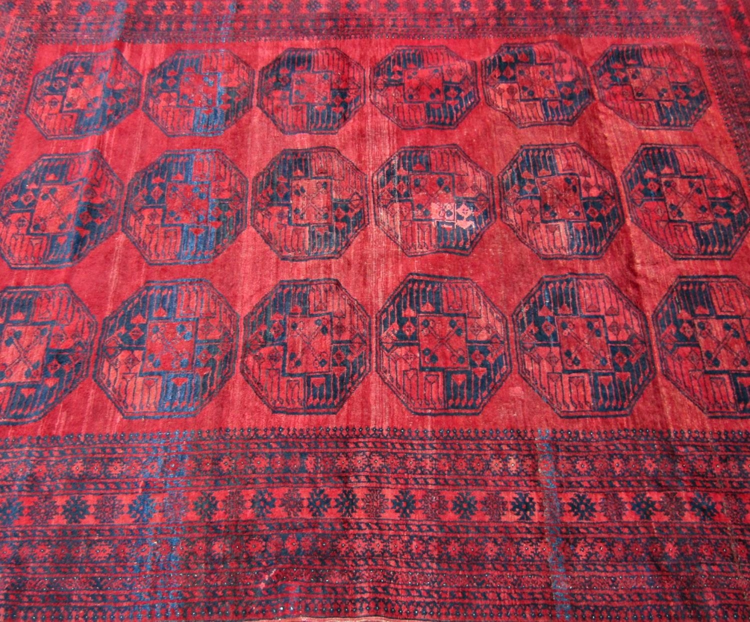 A large Afghan designed carpet with a central panel of elephant feet on a red ground. 310cm x - Image 2 of 3