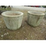A pair of weathered cast composition stone garden planters in the form of coopered half barrels,