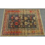 A Middle Eastern designed carpet with a dense floral pattern on a dark blue ground. 190cm x 137cm.