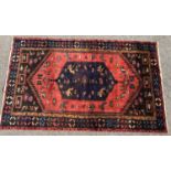 A Saveh rug with a lozenge shape blur medallion with a pink border depicting stylised birds and