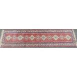 A Middle Eastern designed runner with single row of interlocking medallions in pinks and blues,