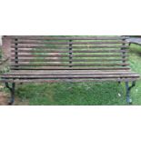 A vintage garden bench with weathered timber slatted seat and combined back raised on sprung steel