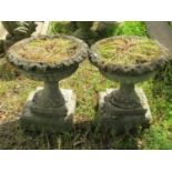 A pair of weathered composition stone garden urns, the squat circular lobed bowls with flared