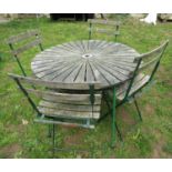 A weathered circular garden table with hardwood sunburst patterned top raised on green painted