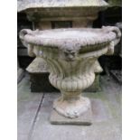 A weathered cast composition stone garden urn with circular lobed and fluted body, flared