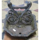A 19th century cast iron boot scraper with scrolling foliate detail and canted rectangular tray base