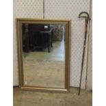 A rectangular gilt framed mirror with bevelled edge plate, 85cm x 60cm approx and walking cane and