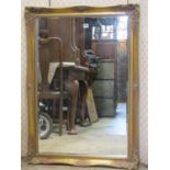 A contemporary mirror, moulded and swept gilded frame, bevelled edge plate, 105 cm x 75 cm