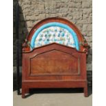 A Victorian mahogany single bedstead, the arched panelled headboard with carved detail supporting