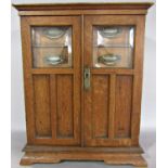 An early 20th century oak cabinet, with glazed doors opening to reveal a fitted interior of four