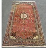A Middle Eastern carpet with a central lozenge shaped medallion and stylised flowers, on a pink