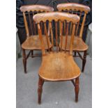 A set of three 19th century Windsor elm and beechwood stick back kitchen chairs with saddle shaped