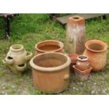 A weathered terracotta square tapered pedestal with square base and repeating foliate detail