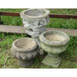 Three weathered cast composition stone garden urns of varying size and design together with a garden