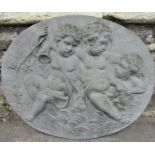 A cast oval wall plaque with frolicking cherub raised relief detail, 67 cm x 56 cm high