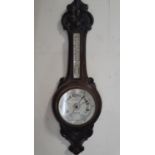 An Edwardian aneroid barometer, the oak case with carved finish with porcelain dials
