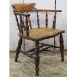 A 19th century smokers bow or captains type chair with turned spindle back over a cane panelled