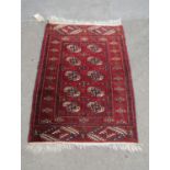 A Turkoman rug with a central panel of elephant foot gul on a dark red ground, 110cm x 85cm.