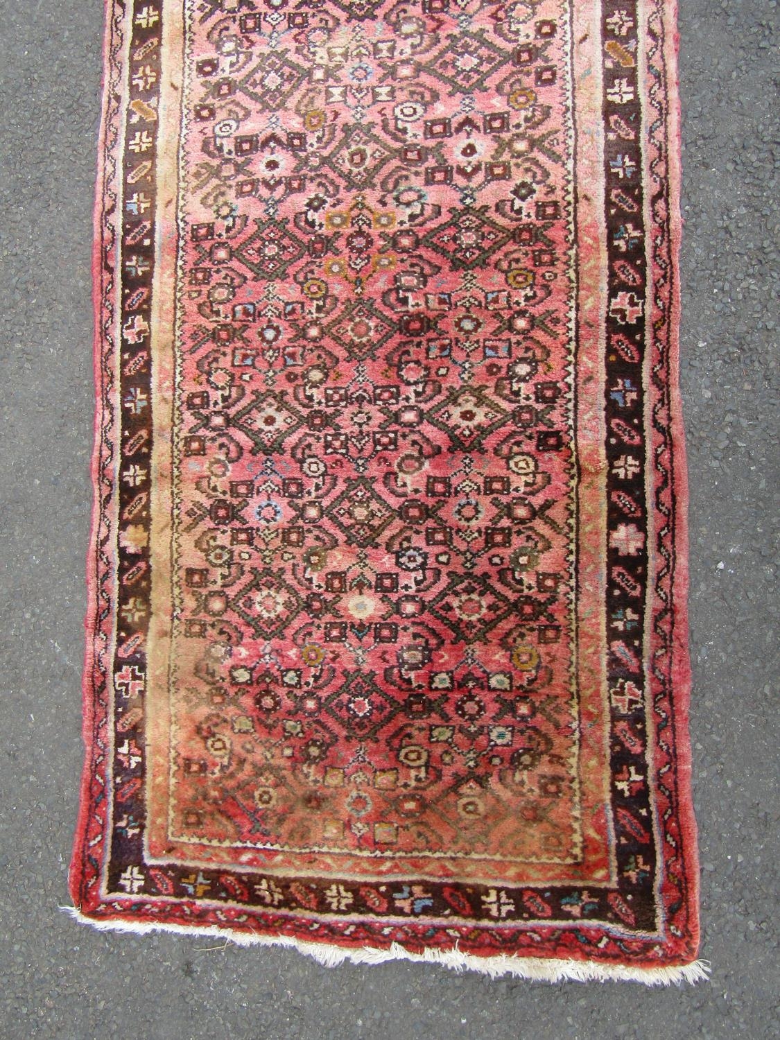 A Hamadan runner with a repeating geometric pattern on a predominantly pink ground, 500cm x 88cm. - Image 2 of 3